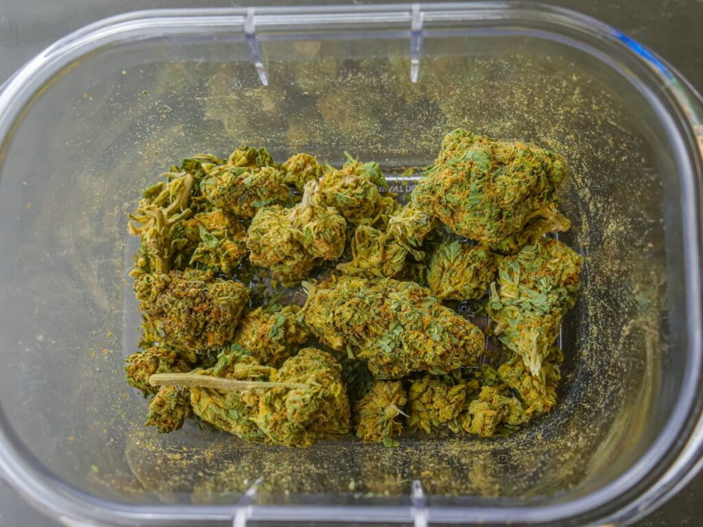 High-quality close-up image of dried cannabis buds in a clear glass container, showcasing texture and detail.